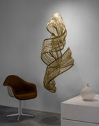 Genesis Vertical Floating Knit Sculpture by Terzani in brass, suspended in a minimalist workspace.